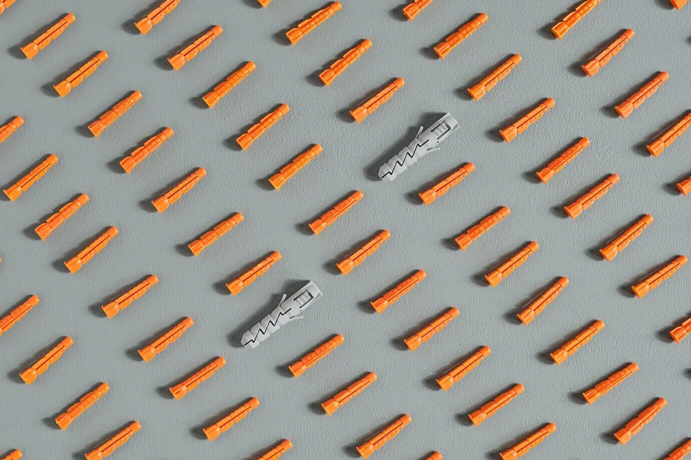 Nahtloses Muster aus roten Kunststoffdübeln auf Grau.